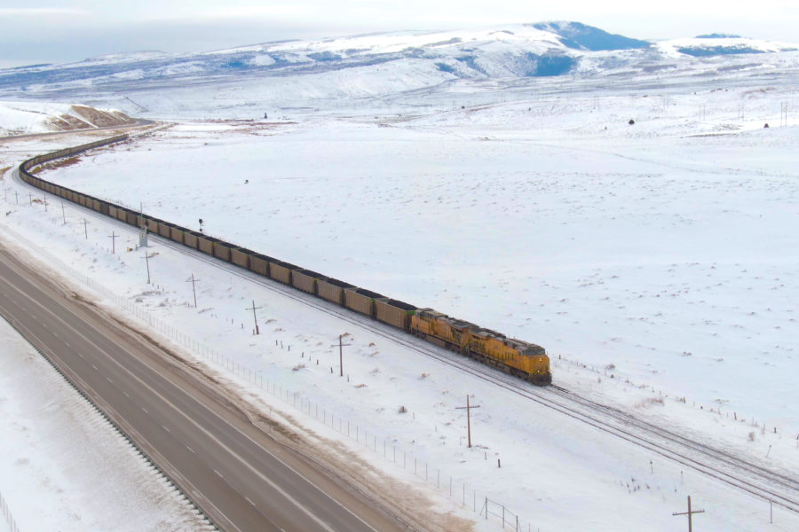 locomotive with open top hoppers with coal coming down a snowy mountain